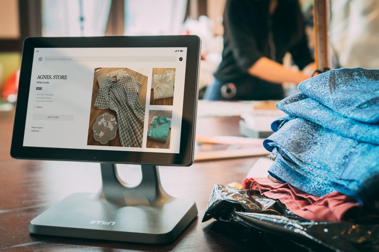 Home A digital point-of-sale system in a small fashion boutique with clothes displayed on a tablet.