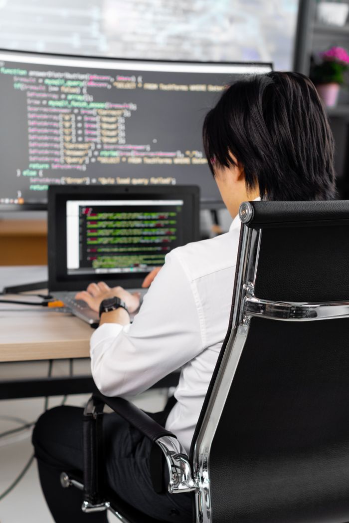 About Professional software developer writing code at a desk in a modern office environment.